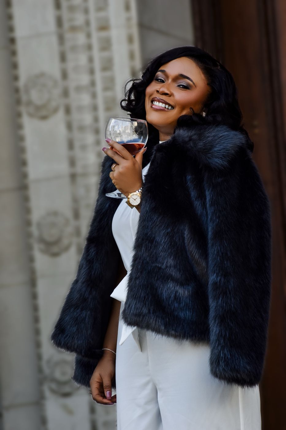 Portrait of a smiling woman in a fur coat holding a glass, photographed by Prince GEE17 Media